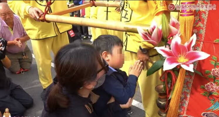 媽媽抱兒子泣求媽祖保佑,男童雙手合掌拜向媽祖。(圖擷取白沙屯媽直播) 媽媽抱兒子泣求媽祖保佑,男童雙手合掌拜向媽祖。(圖擷取白沙屯媽直播)
